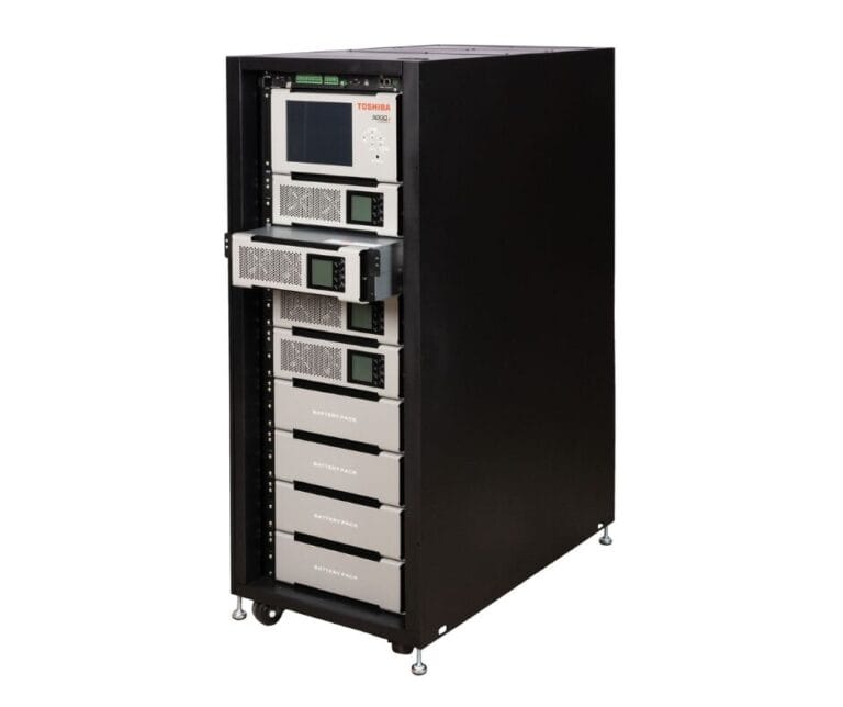 Toshiba battery storage system with multiple stacked battery packs and digital displays in a black cabinet.